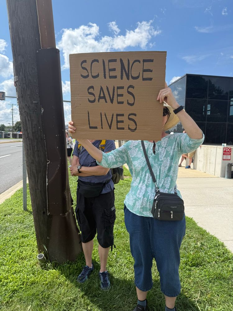 Women behind another women holding us a sign that says science saves lives