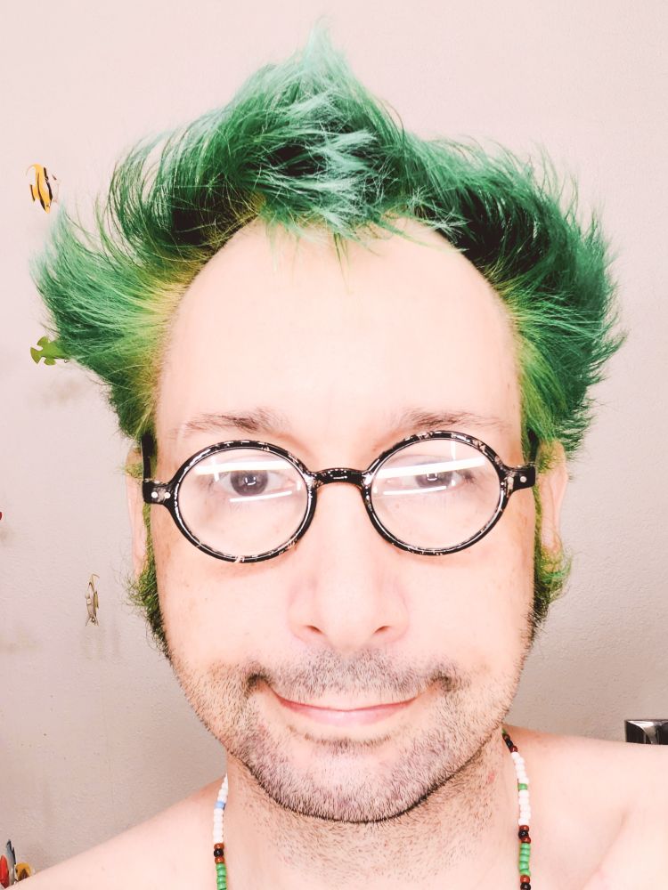 Me, a Caucasian masc non-binary autistic person with green hair. It is tinted slightly teal.