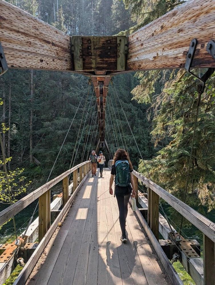 The sun is shining. Wearing a green backpack, I walk over a wooden bridge into the woods. A couple crosses the bridge in the other direction.