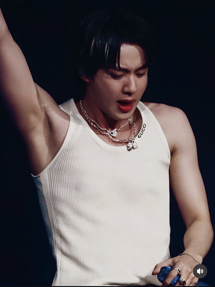Seokjin in Hamsterdam, final concert of his tour. See-through white tank top, arm up exposing a hairless pit, nip nops visible through the cloth, his dark hair contains white highlights, red lips parted and looking down. 🥵