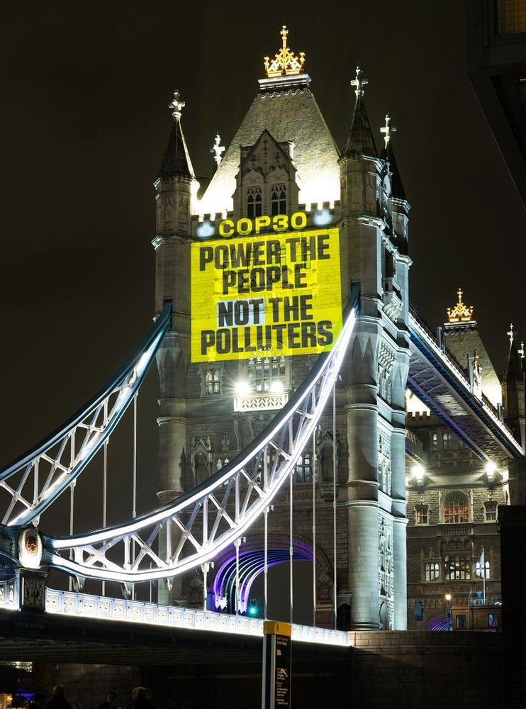 Photo of yellow projection on the Tower bridge reading “COP30 POWER THE PEOPLE NOT THE POLLUTERS”.