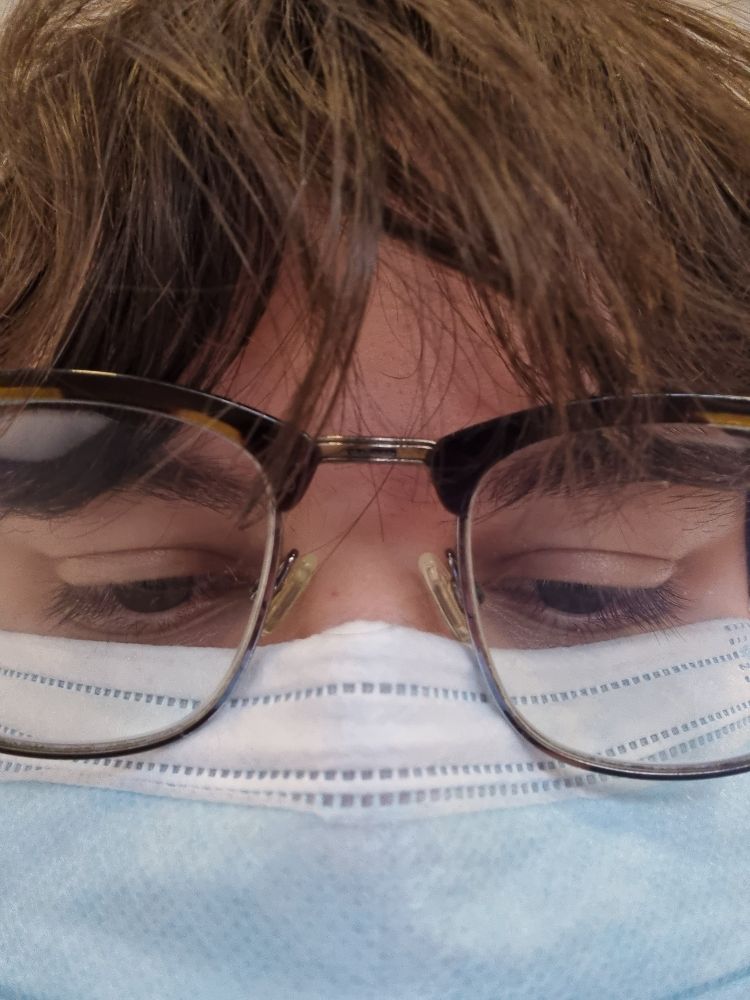 It's me, a closeup of me, brown fringe, glasses and a blue face mask, looking down