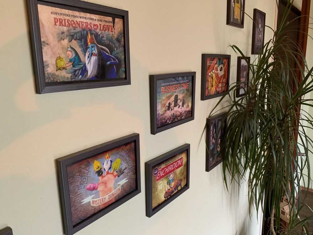 Wand mit Bilderrahmen. In den Rahmen, Bilder aus der Serie ‚Adventure Time‘. 