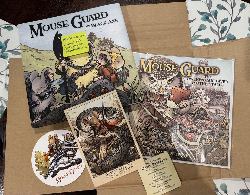 Mouse Guard the Back Axe book, Mouse Guard the Owlhen Caregiver & Other Tales book, and various artwork with David Petersen contact info card. 