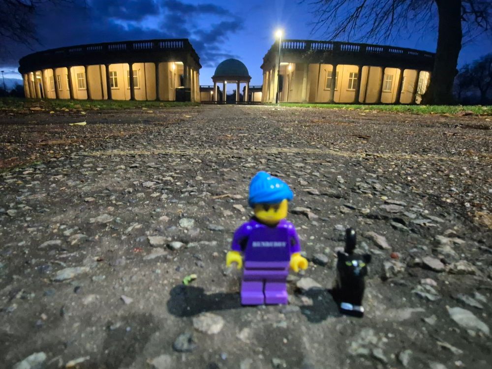 Same view with legorunbuddy and legorunkitten.  They are on the path and in background is bandstand and rotunda its all lit up against the early morning ink blue sky.