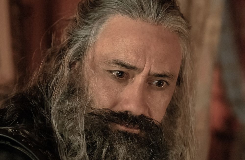 a zoomed in close-up of ed teach's very focused face while he's sitting on the edge of stede's bed, fixated on his bare naked chest (our flag means death s1e4 set photo by aaron epstein)
