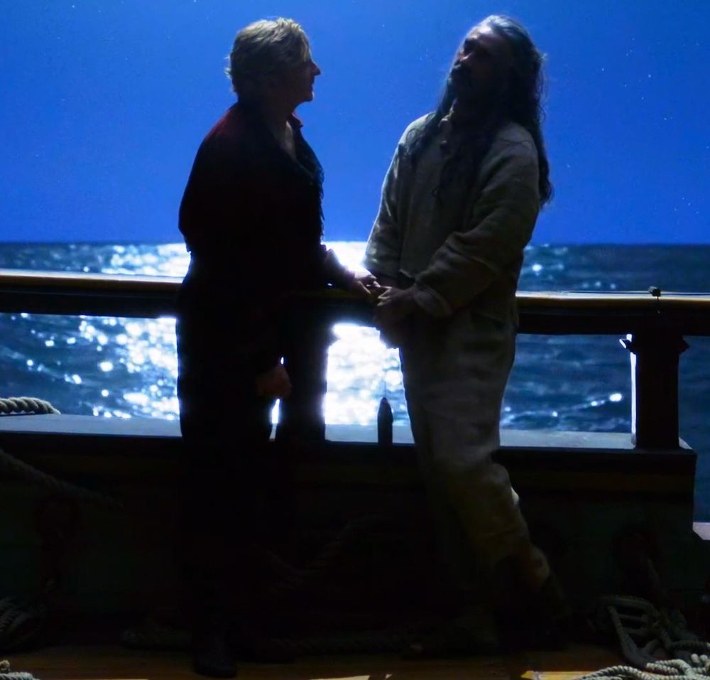 ed teach leaning away from stede with a foot nervously picked up to be on his toes as he's about to set boundaries, stede is tenderly listening and not leaning too far in, with his hand just barely touching ed's hands to support him without crossing over those new boundaries (our flag means death s2e5)