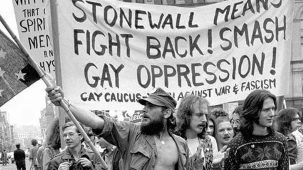 LGBTQ rights protest with protesters holding a sign that says "Stonewall means fight back! Smash gay oppression!"