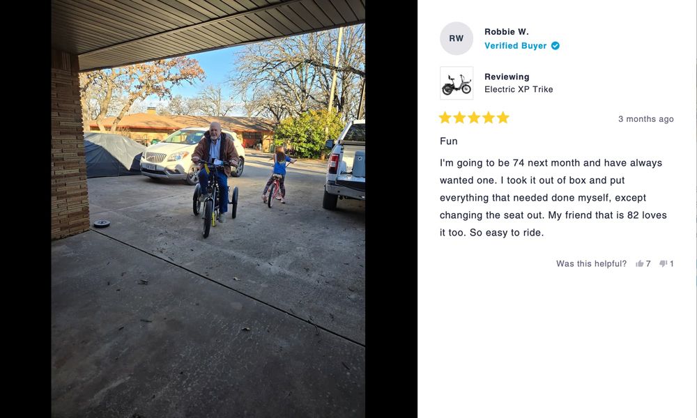 A photo of an old man with a goatee on an e-trike next to his granddaughter on a pink bike.

The review reads: I'm going to be 74 next month and have always wanted one. I took it out of box and put everything that needed done myself, except changing the seat out. My friend that is 82 loves
it too. So easy to ride.