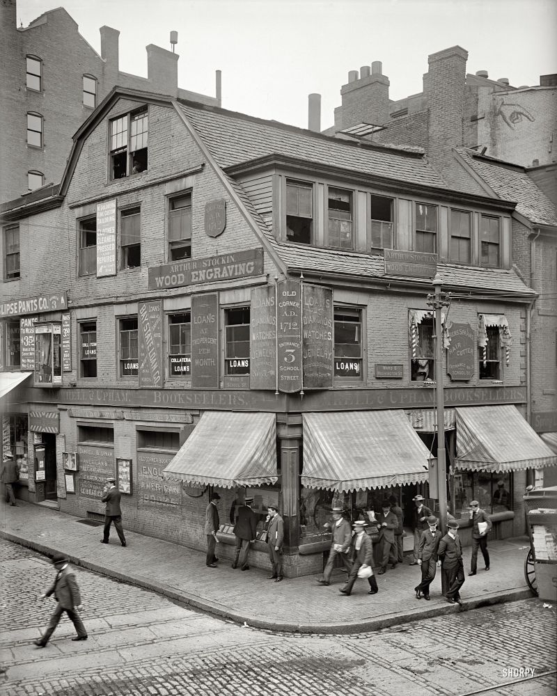 Street in front of the Old Corner Bookstore in Boston in the 1900s with a horse carriage off to the right, cobblestone street, and sidewalk with a curb setting itself apart from the street