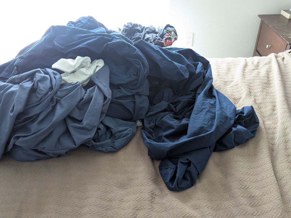 A pile of blue sheets on a bed