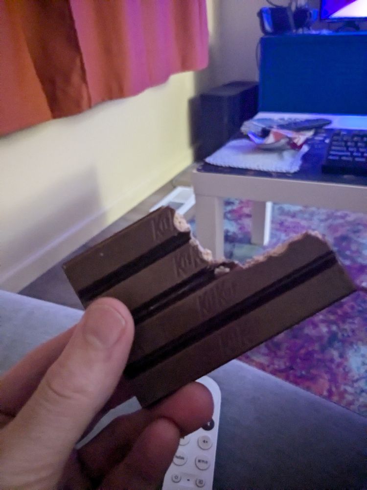 A picture of me holding a KitKat where I've taken a bite without breaking it apart into its component sticks. I am sure that this is a contentious decision.