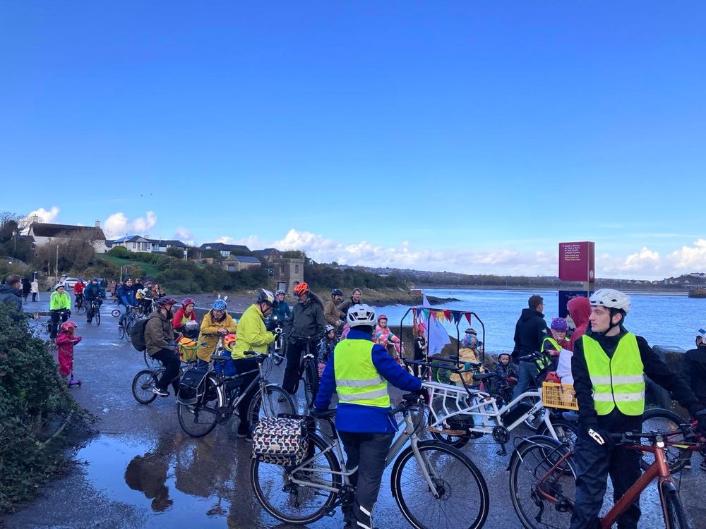 We’re beside the sea. To the middle distance over on the right there is a sheltered bay. To the left, leading away is a wide promenade, with prominent puddles. The subject of the photo is the large number of people, mostly dressed sensibly, some with high viz,some in Halloween kit, but all with a bike or scooter. The sky is cloudless blue, despite the fact that the rain was hammering down ten minutes previously 