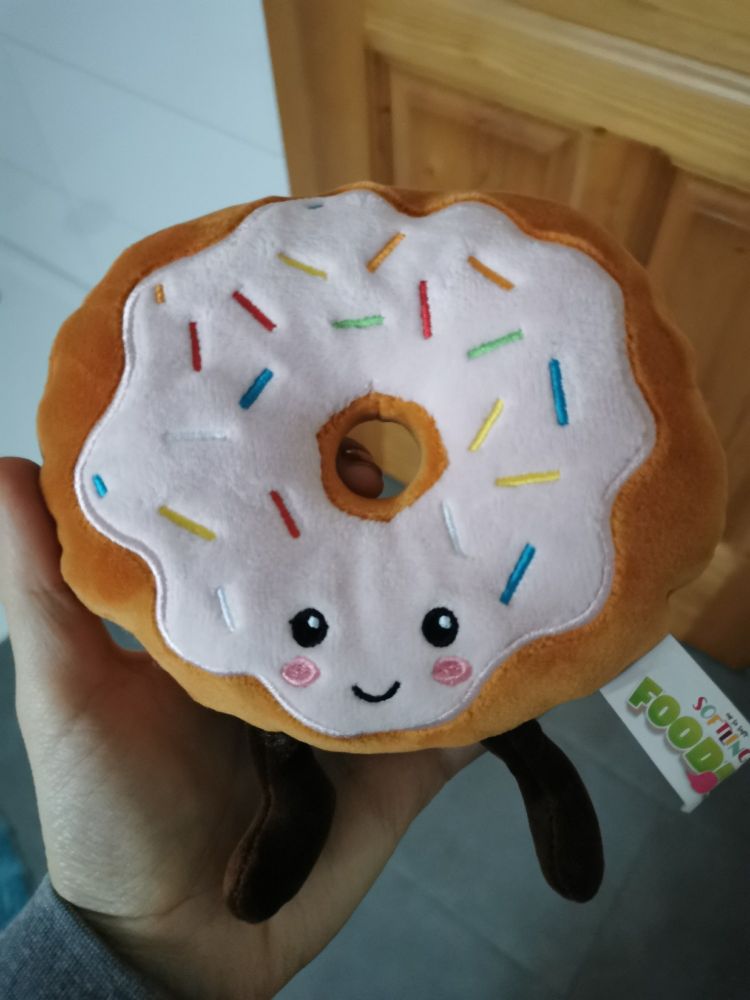 Stoffdonut wie Stofftier, mit Gesicht und Beinen, oben rosa Glasur mit Streuseln 