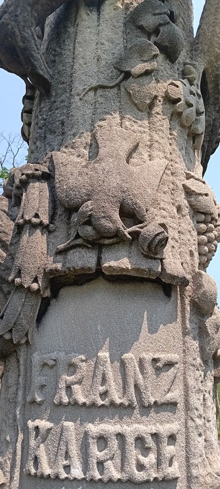 Rustic monument with dove flying down, holding a rose.