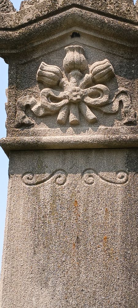 Detail of granite headstone column, carving of three thistle flowers tied with a bow