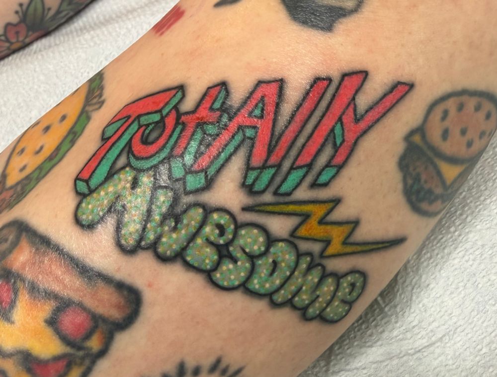 A tattoo that says “totally awesome” in an 80s theme. 