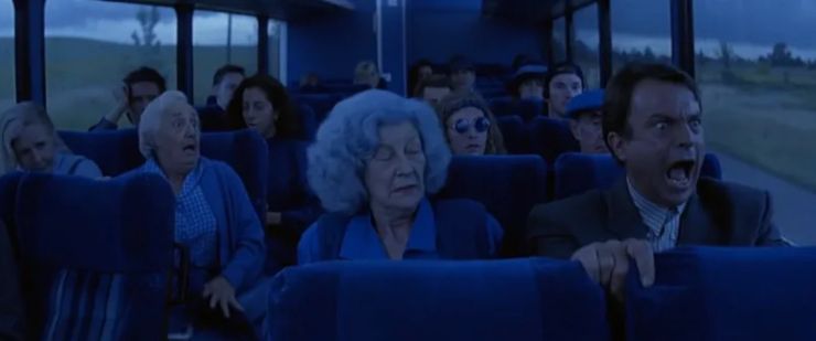 Still from In the Mouth of Madness of a screaming man on a bus, everything around him blue 
