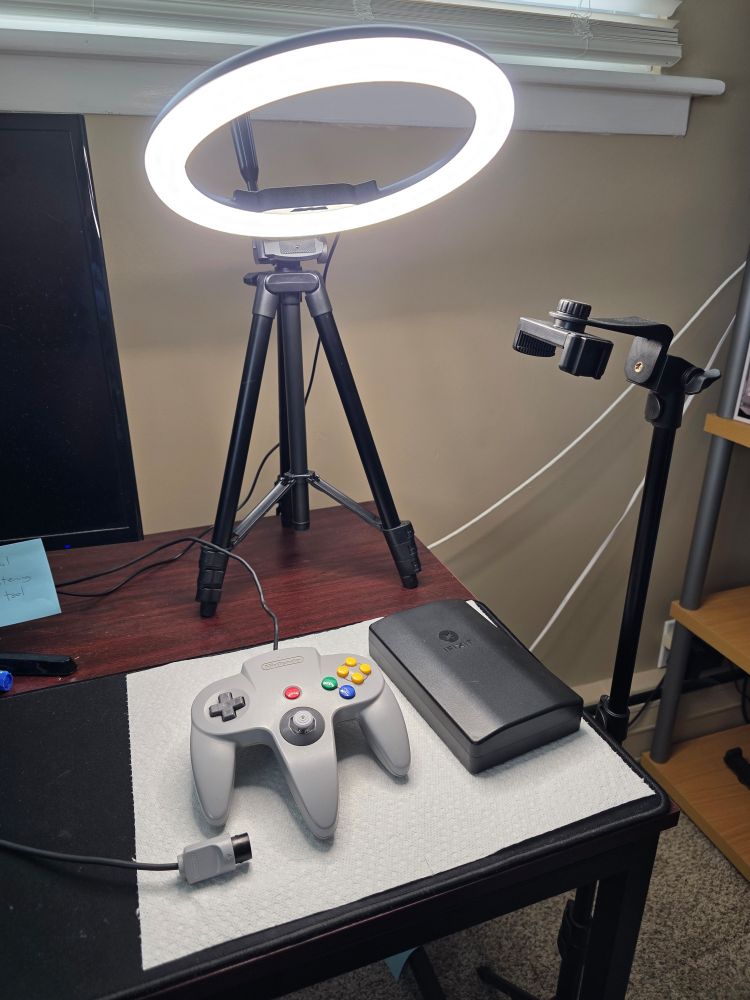 A Nintendo 64 controller illuminated by a ring light. 