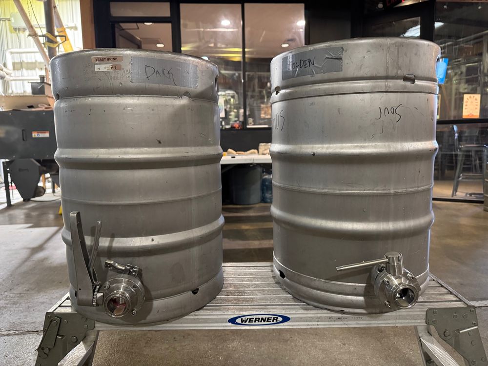 Photo showing two beer kegs, one labeled “dark” and one labeled”golden.”