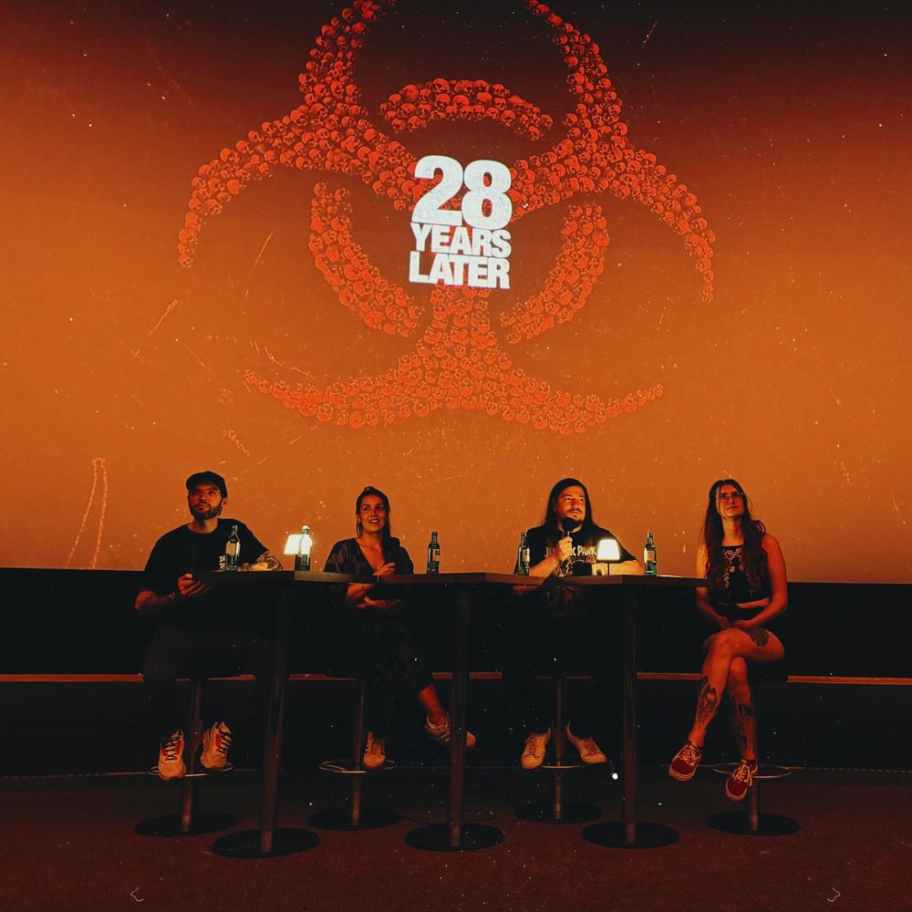 Podcaster im Kino vor der Leinwand, auf dieser ist das 28 Years Later Film Logo zu sehen 