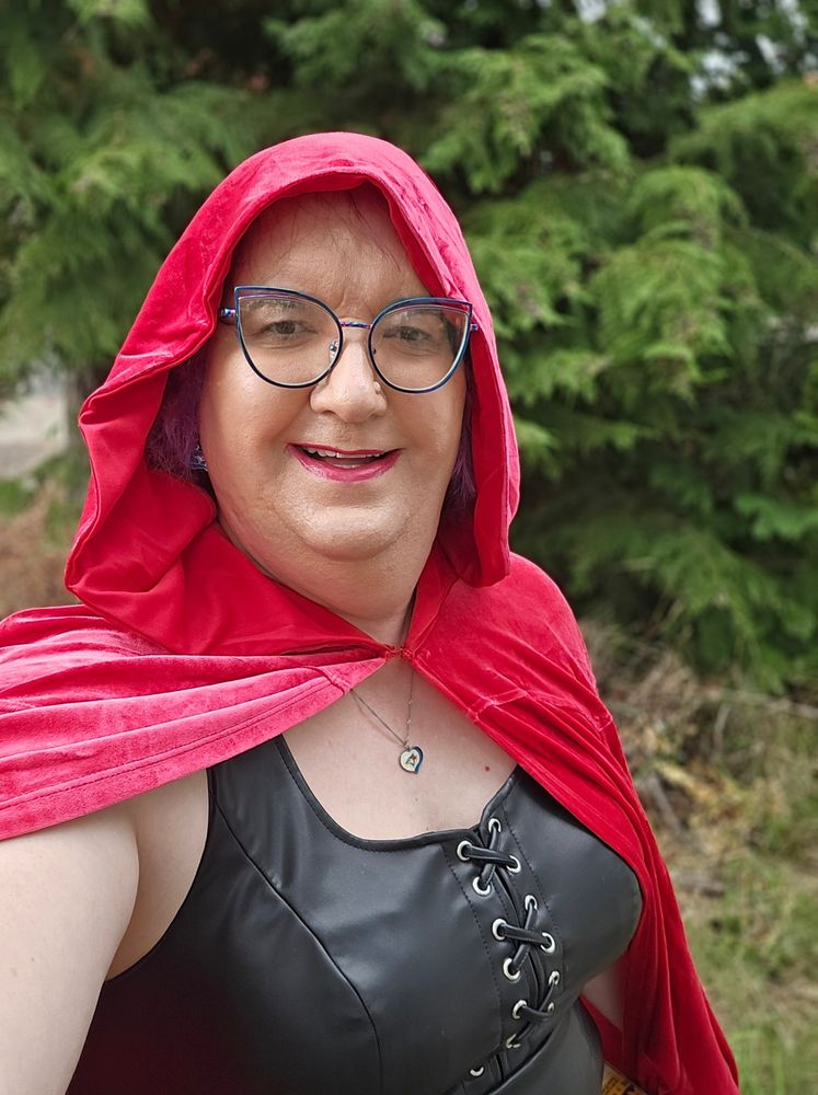 Selfie.  White woman with a faux leather top and a red hood.  