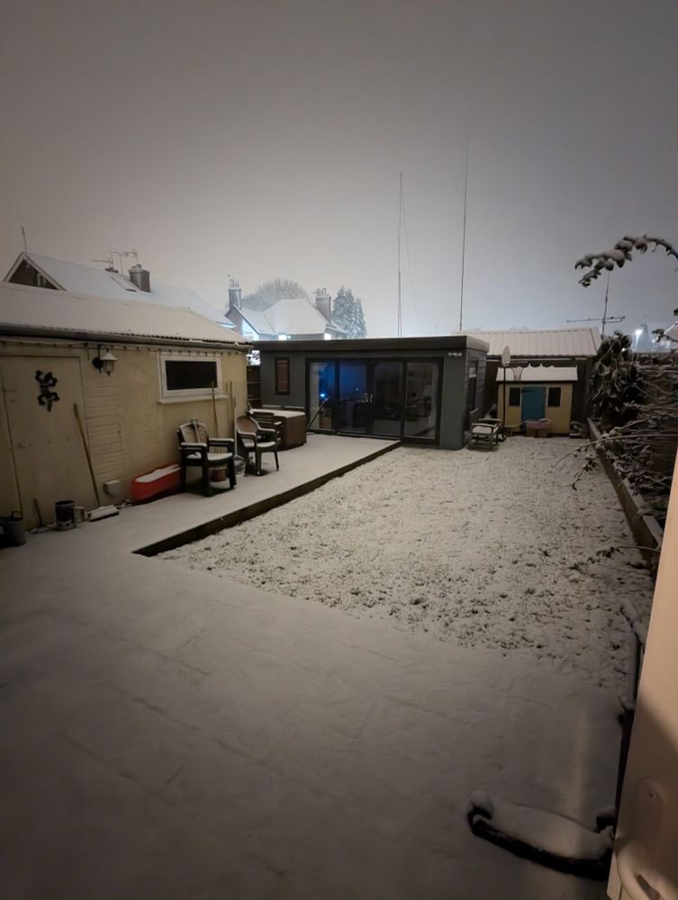 A garden, taken at night, showing approx 1cm of snow covering the ground and buildings