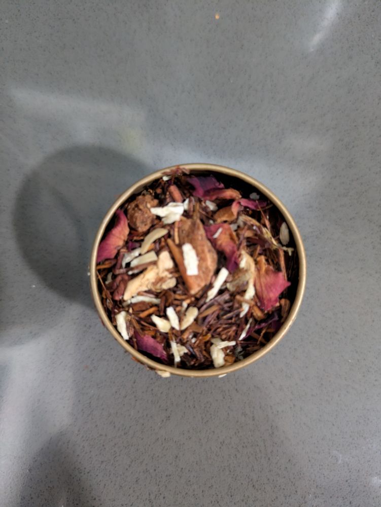 A small gold tin of red rooibos tea with flakes of almond and cinnamon.