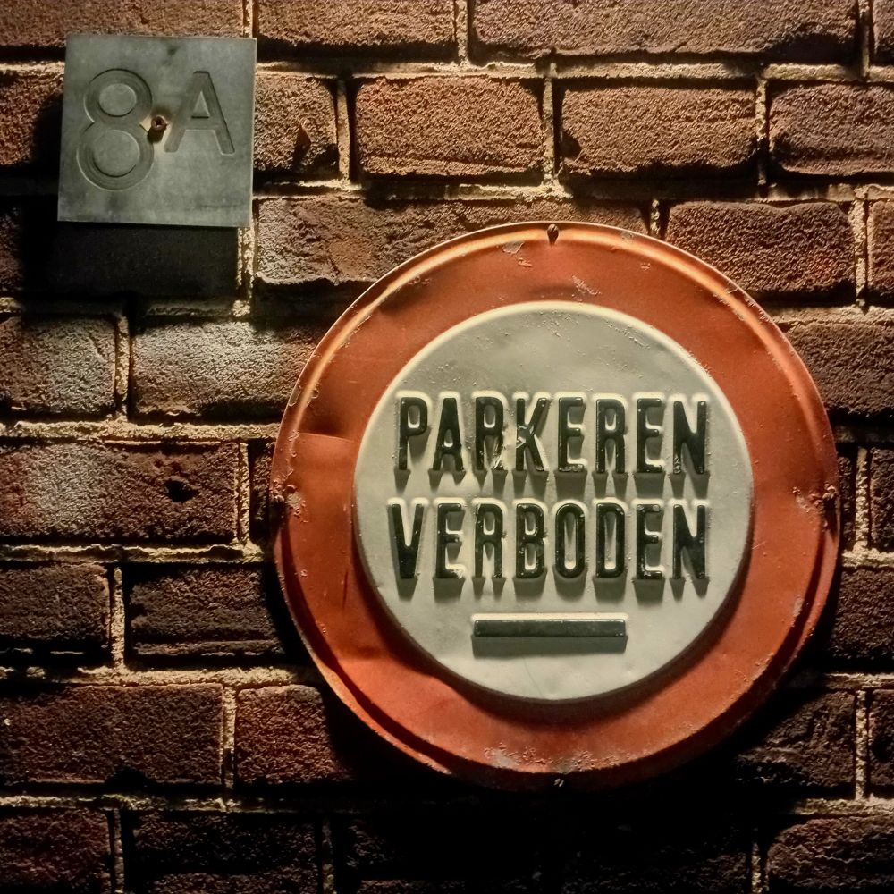 A No Parking sign on a brick wall at night.