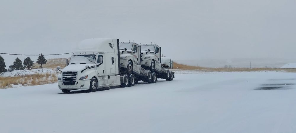 New trucks piggybacking for transportation to delivery in a snowy parking lot 
