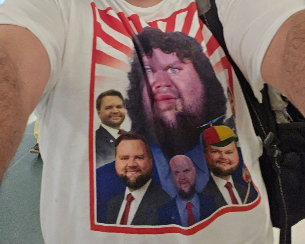 A white t-shirt, with a collage of many alternate J.D. Vance memes, where he looks strange in each one, such as being chubbier, having long hair or no hair, having a variety of different facial hair styles, wearing a propeller hat, drooling something green, etc.