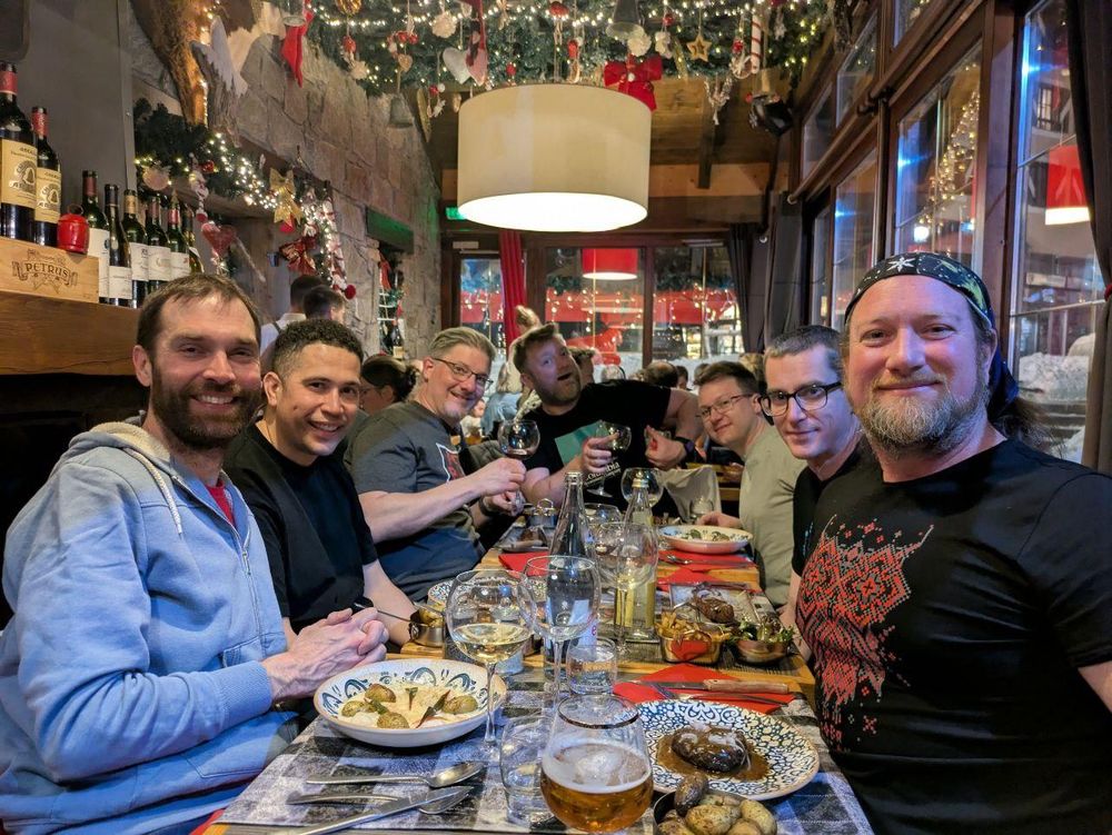 A picture of 7 guys around a dinner table in a restaurant at the end of their trip, looking appropriately happy.