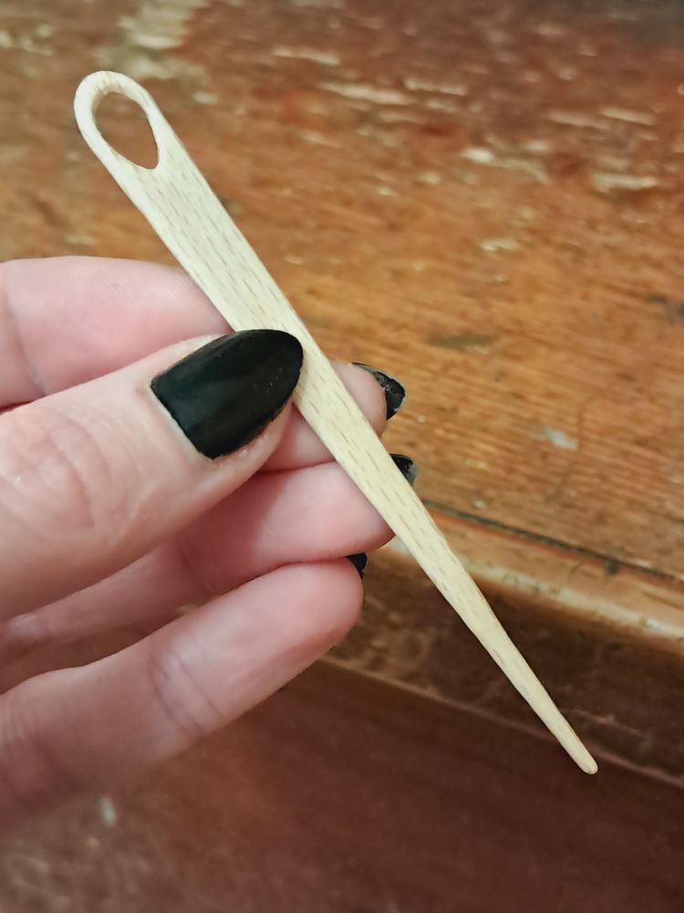 a popsicle stick carved into a darning needle