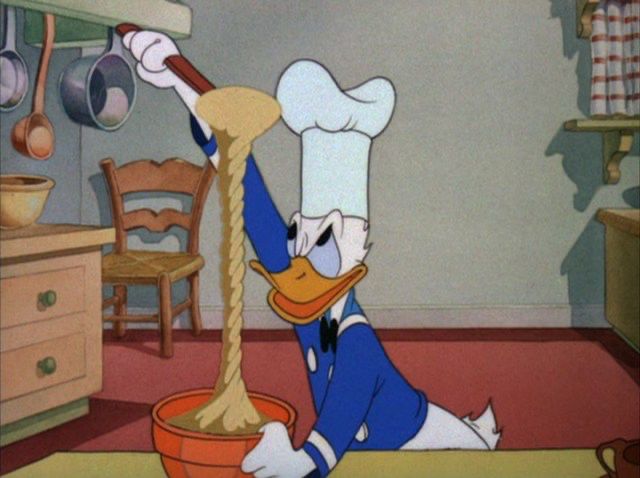 Donald Duck, wearing a chef’s hat, mixes a bowl of batter that has somehow twisted itself into a braid