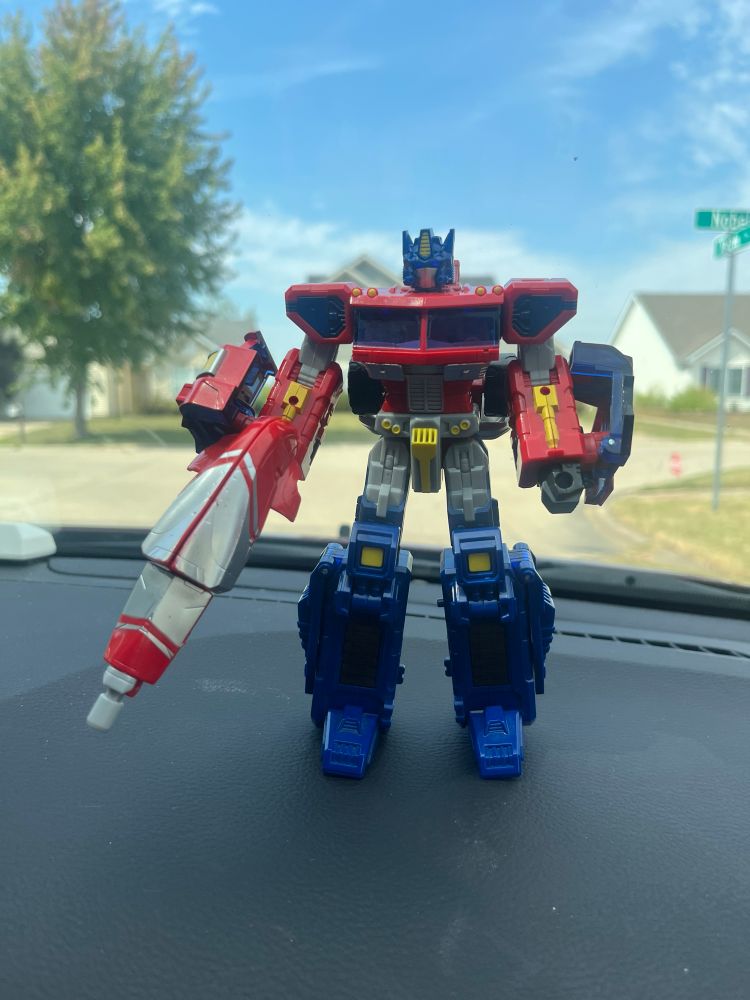 2006 Classics Optimus Prime standing on a car dashboard. He is only missing his smokestacks gun, and is in otherwise incredible shape.