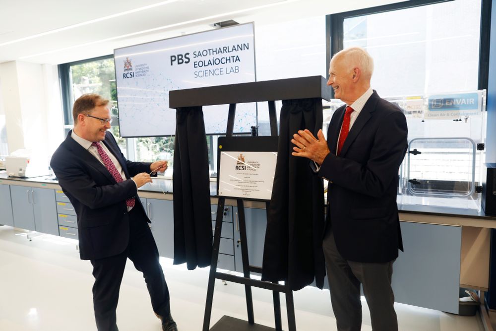 Professor Cathal Kelly, Vice Chancellor of RCSI, and Minister James Lawless TD unveiling a commemorative plaque during the official opening of RCSI’s redeveloped School of Pharmacy and Biomolecular Sciences. The two men are smiling and standing in a modern laboratory setting, with RCSI and PBS Science Lab branding visible in the background.