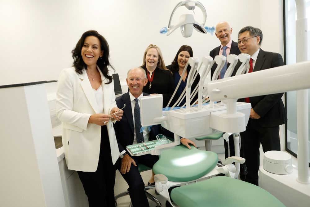 Minister Jennifer Carroll MacNeill stands smiling beside a dental chair, joined by the President of RCSI, the Vice Chancellor of RCSI, the Head of the RCSI School of Dentistry and other guests celebrating the launch of the RCSI Dental Education Centre in Sandyford.