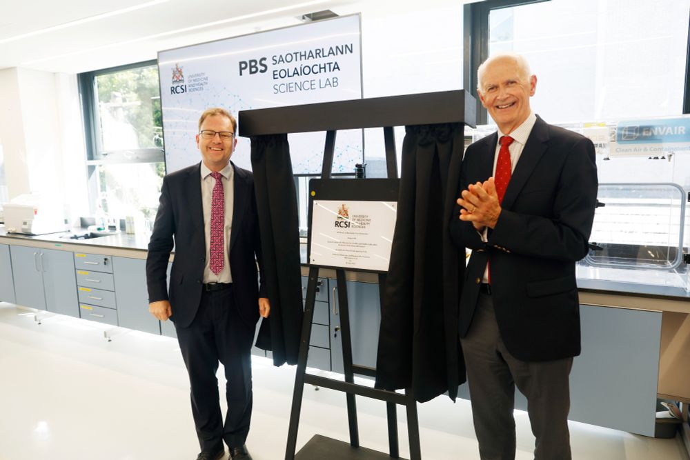 Professor Cathal Kelly, Vice Chancellor of RCSI, and Minister James Lawless TD unveiling a commemorative plaque during the official opening of RCSI’s redeveloped School of Pharmacy and Biomolecular Sciences. The two men are smiling and standing in a modern laboratory setting, with RCSI and PBS Science Lab branding visible in the background.