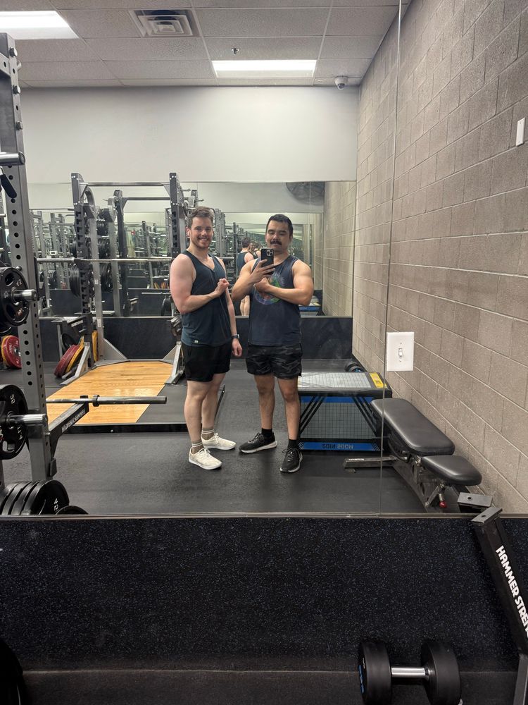 Two men in a gym mirror flexing