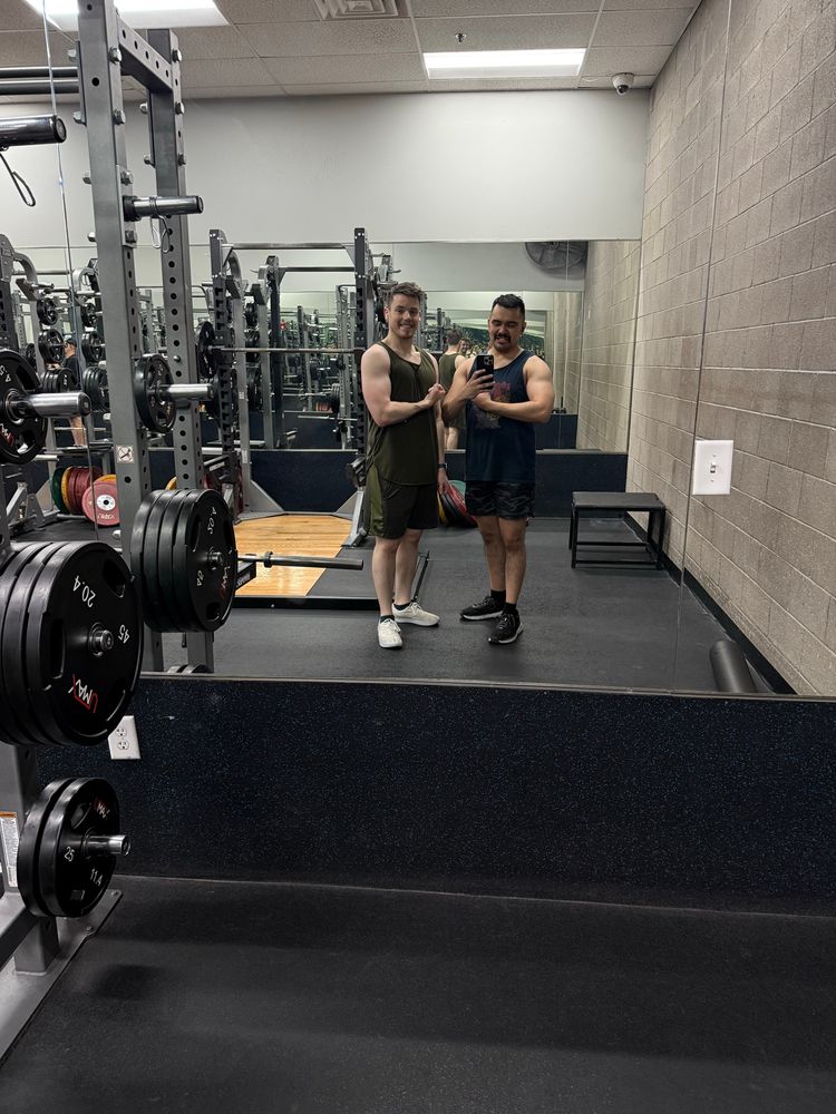 Two guys in a weight lifting room flexing