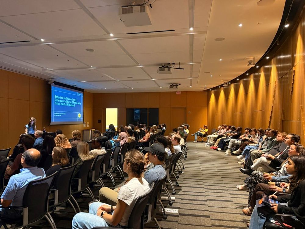 A full seminar room of faculty, students and community members listening to the oral presentation by a second year MIND scholar.
