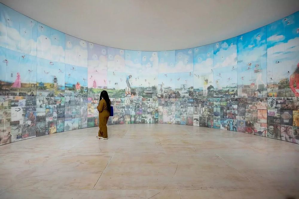 a figure looks at a large-scale installation of imagery printed from newspapers