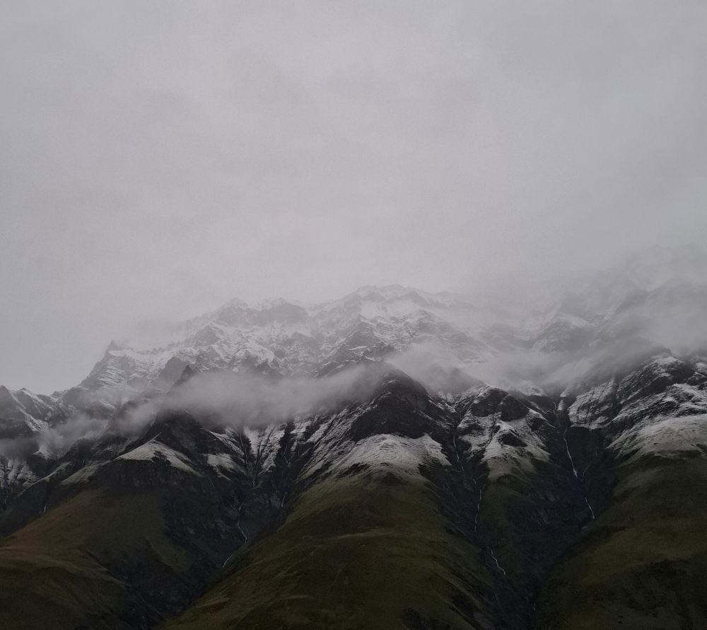 Verschneite Berge über dem Morgendunkel des Tales.