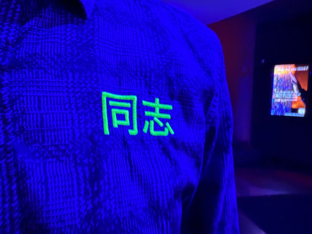 A shirt that says 同志, glowing in black light 