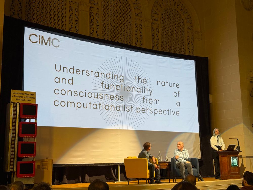 Conference stage with slide with CIMC mission statement: “Understanding the nature and functionality of consciousness from computationalist perspective”