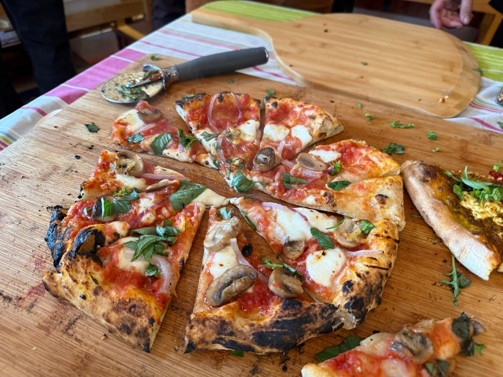 Pizza with mozzarella, mushrooms, and basil on a cutting board 