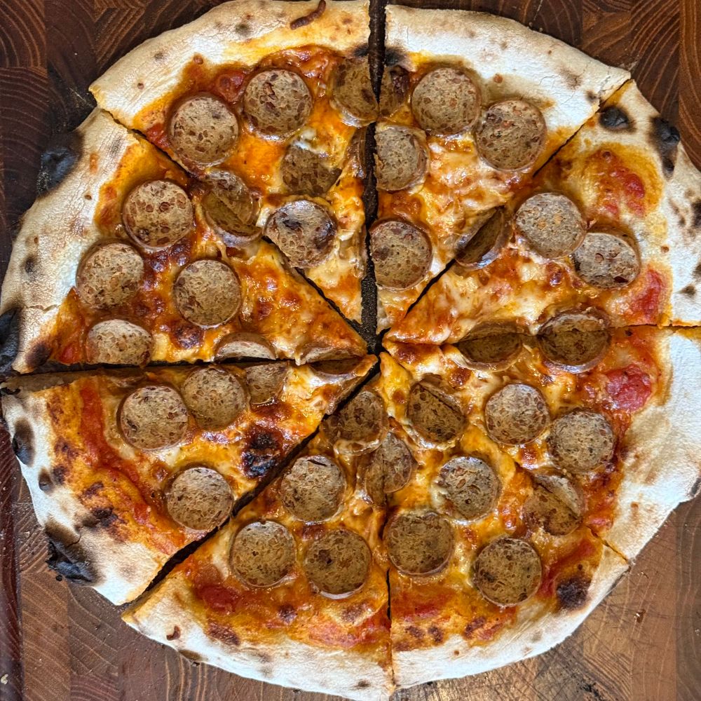 Vegan Italian sausage pizza on a wood cutting board