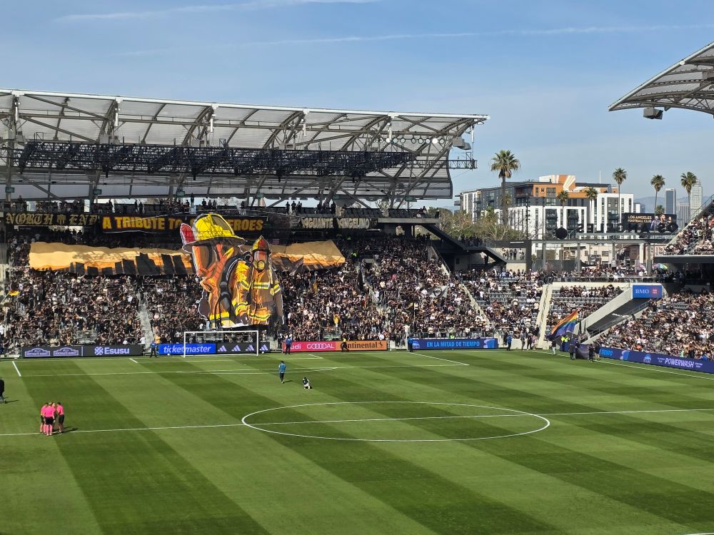 A tifo of a fire fighter in a soccer stadium.