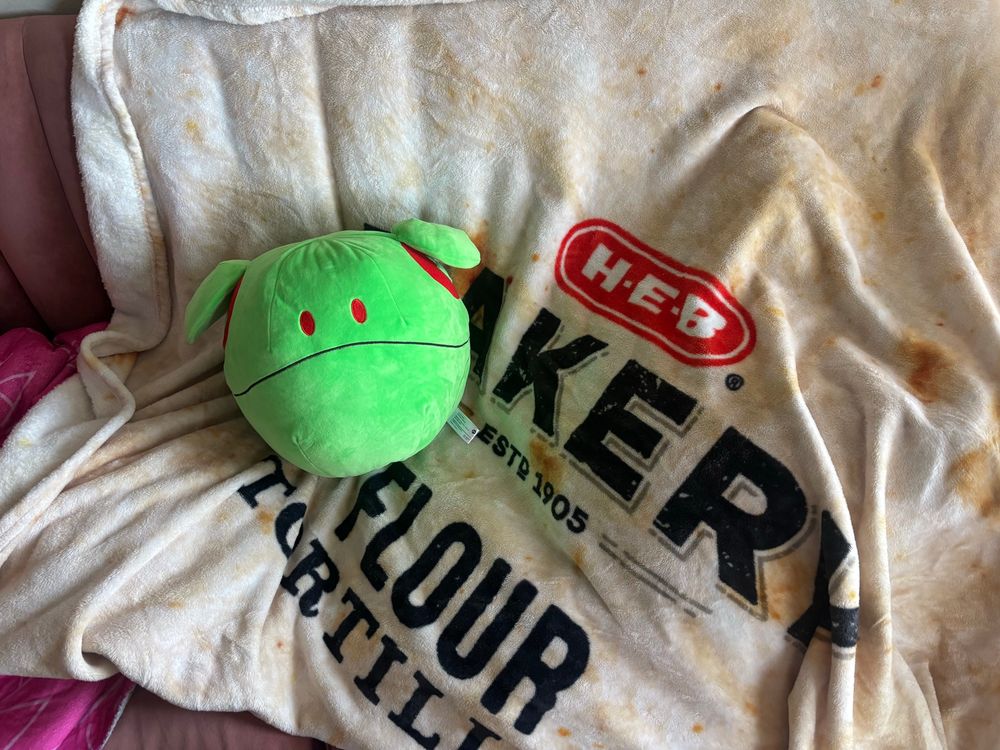 a haro plush from the gundam series on top of a blanket that looks like a bag of heb butter tortillas