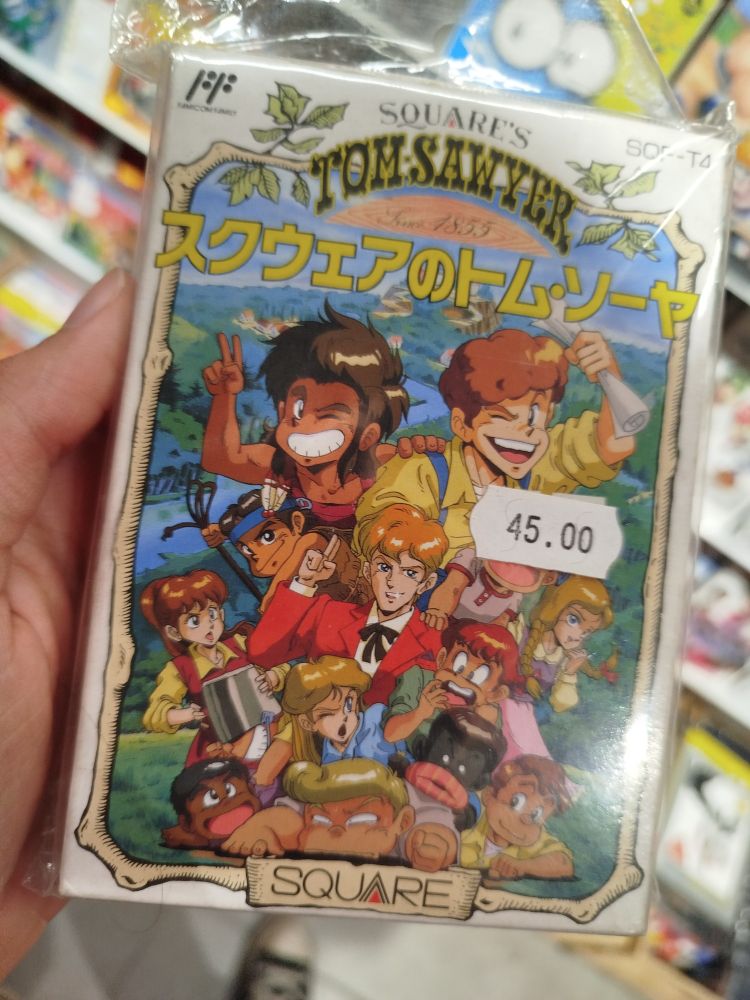 Picture of an original copy of the videogame "Square's Tom Sawyer", for the Famicom. The cover features art of the entire cast, and one of the characters is a racist carlcature of a black person. The copy is priced 45 euros.